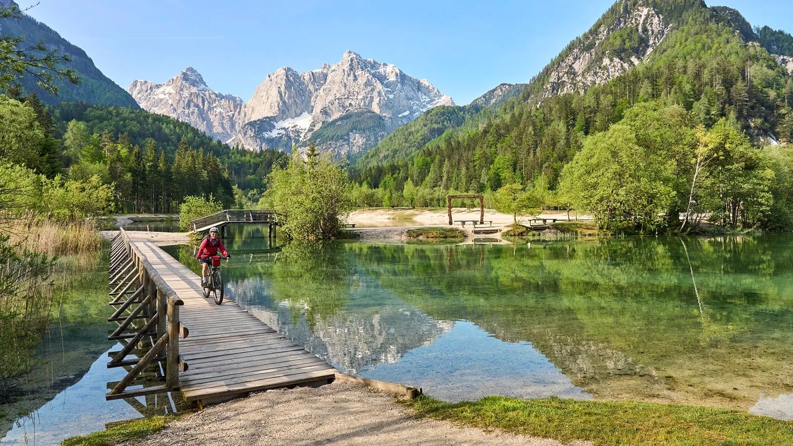 Cyclist crossing a wooden boardwalk at Lake Jasna in Slovenia